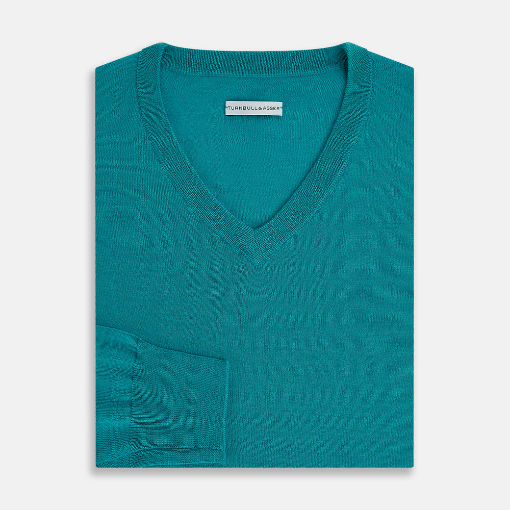 The Turnbull & Asser Turquoise Fine Merino V-Neck Jumper features long sleeves, ribbed cuffs and waistband, shown on a white background—a timeless choice for classic knitwear enthusiasts.