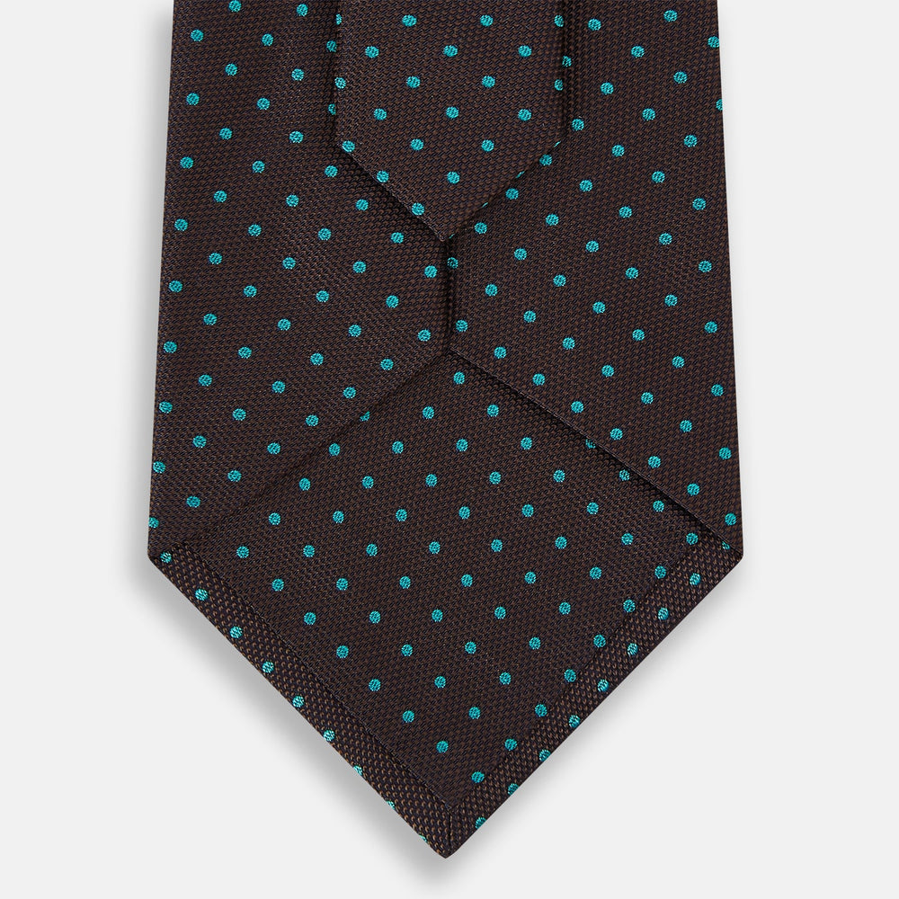 The Turnbull & Asser Turquoise and Forest Green Micro Dot Silk Tie is rolled up, showcasing evenly spaced micro dots on silk, displayed against a plain white background.