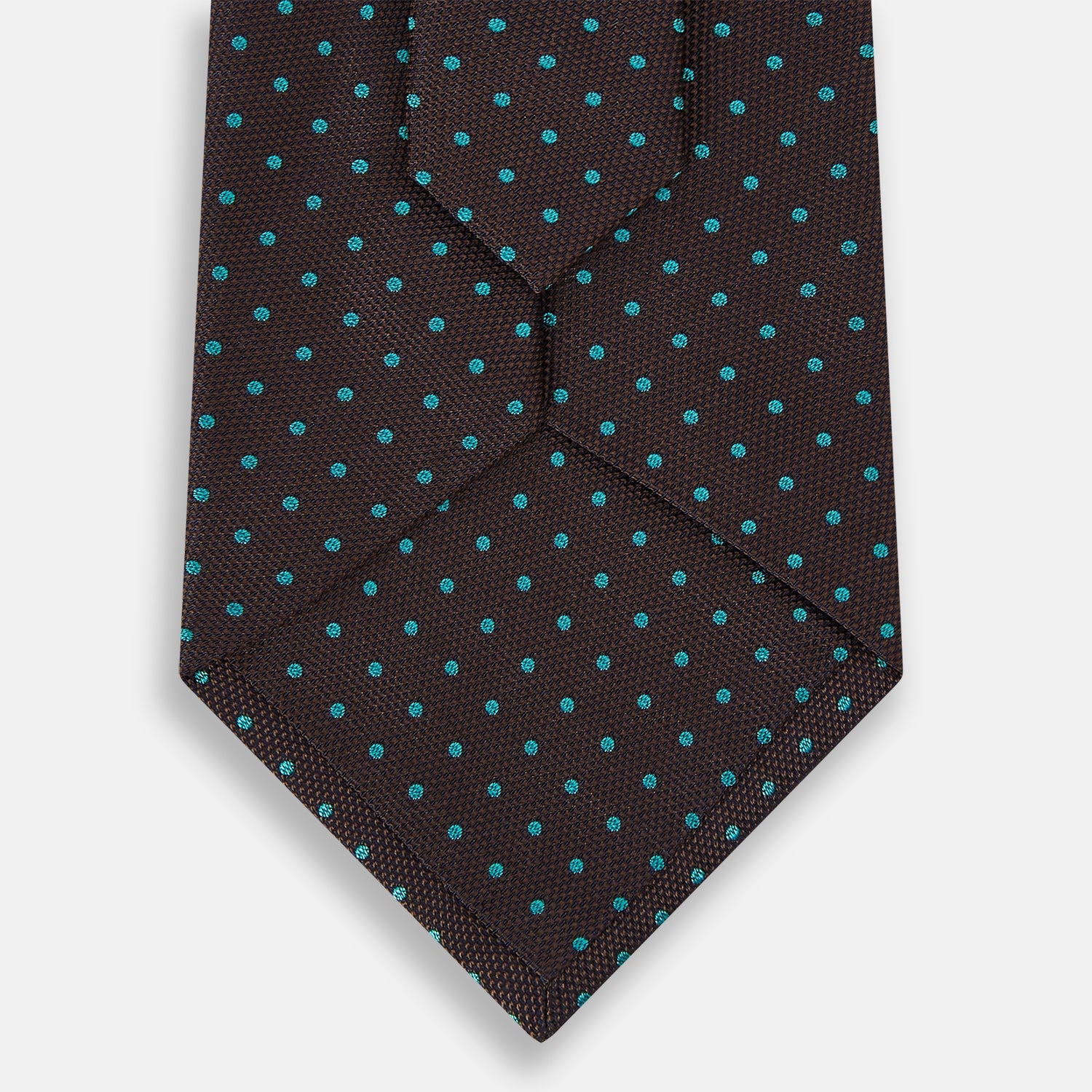 View 3 of product The Turnbull & Asser Turquoise and Forest Green Micro Dot Silk Tie is rolled up, showcasing evenly spaced micro dots on silk, displayed against a plain white background.