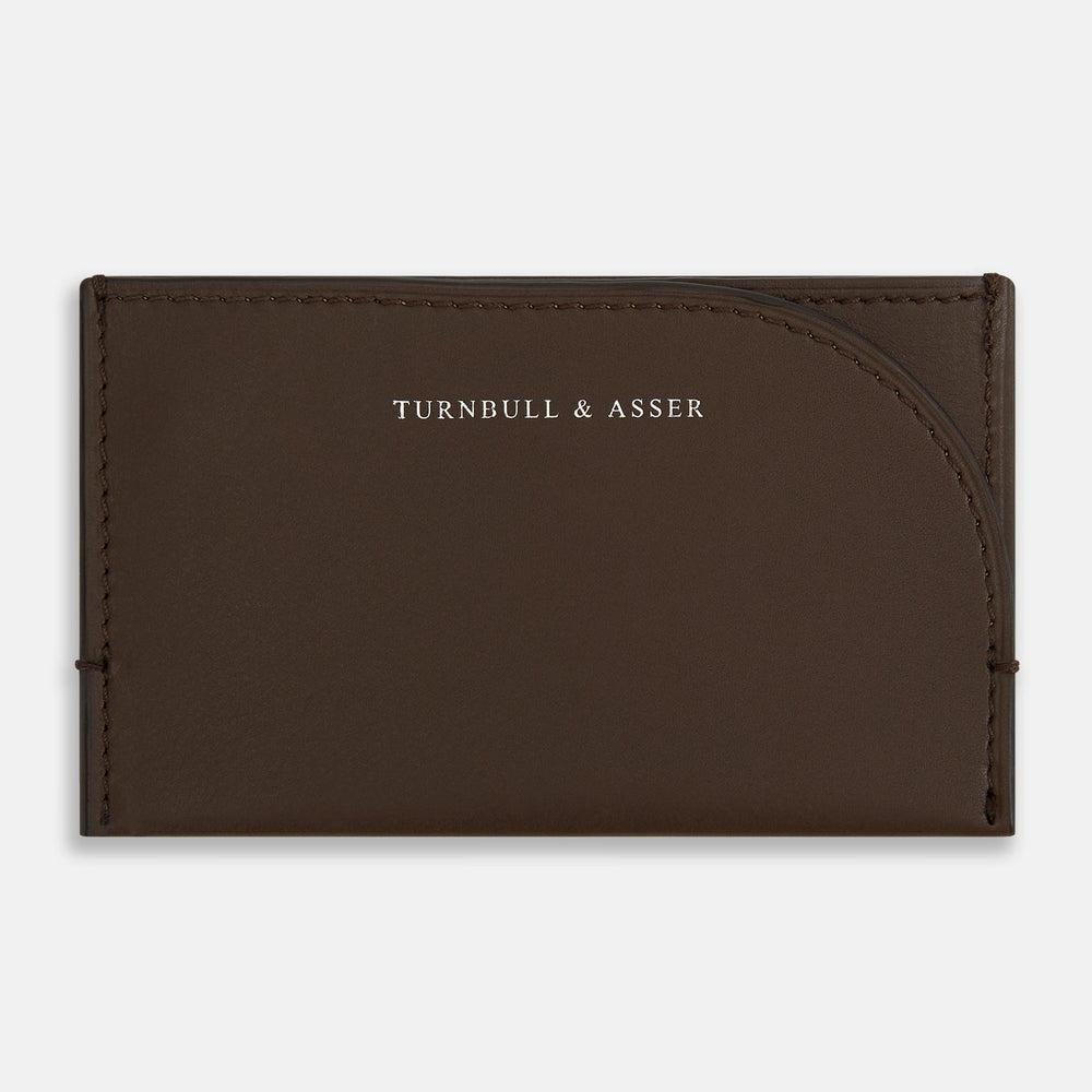 Crafted from dark chocolate leather, the Turnbull & Asser Slim Rounded Card Case features a curved right edge, clean stitching, and the brand’s white embossed logo.