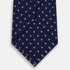 View 3 of product The Pink Dot and Navy Silk Tie by Turnbull & Asser features evenly spaced pink polka dots on navy silk, rolled neatly on a white background—a classic British style ideal for refined occasions.