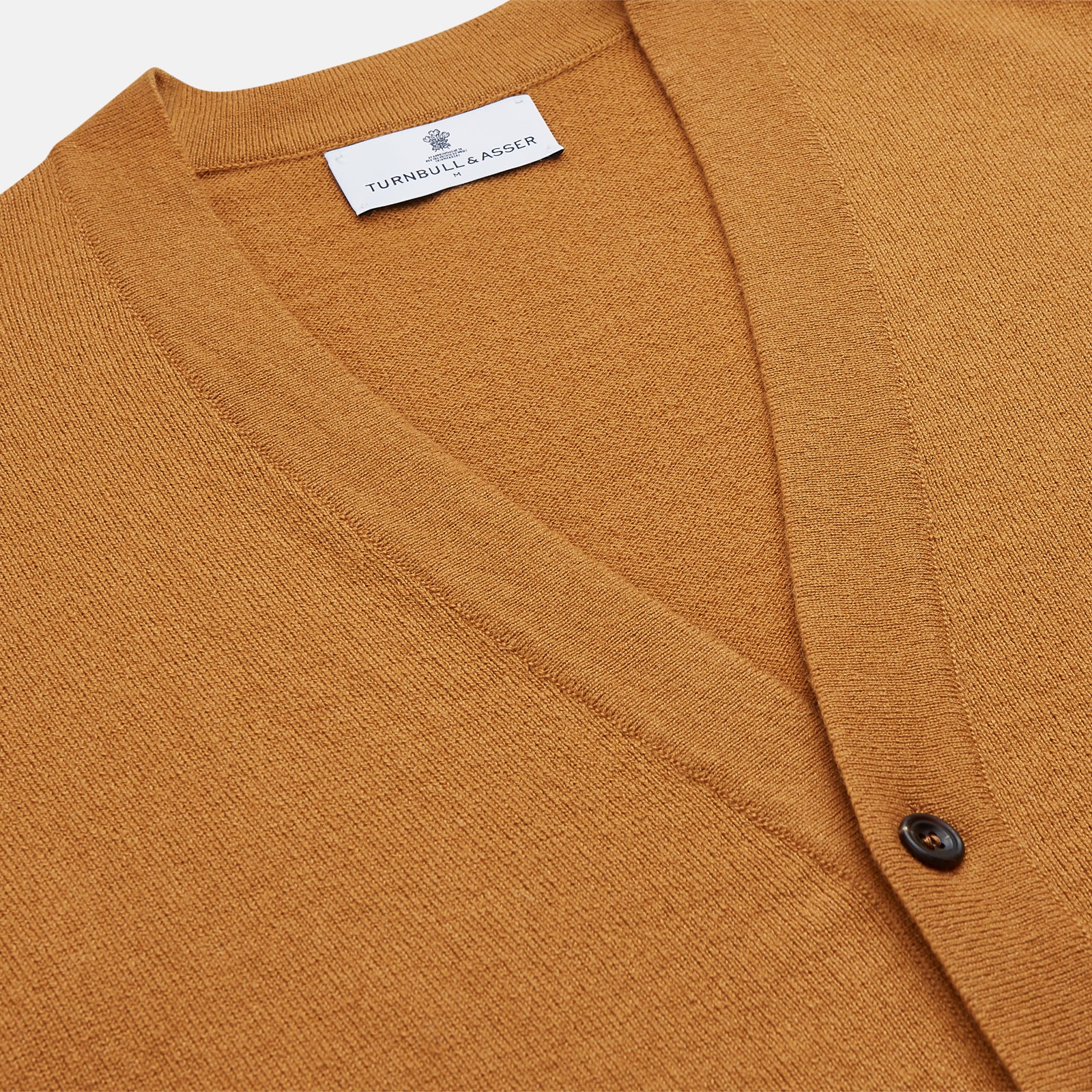 View 2 of product The Turnbull & Asser Golden Brown Cashmere Lachlan Cardigan features long sleeves, front buttons, two front pockets, and ribbed cuffs and hem—a luxurious knitwear piece shown laid flat on a white background.