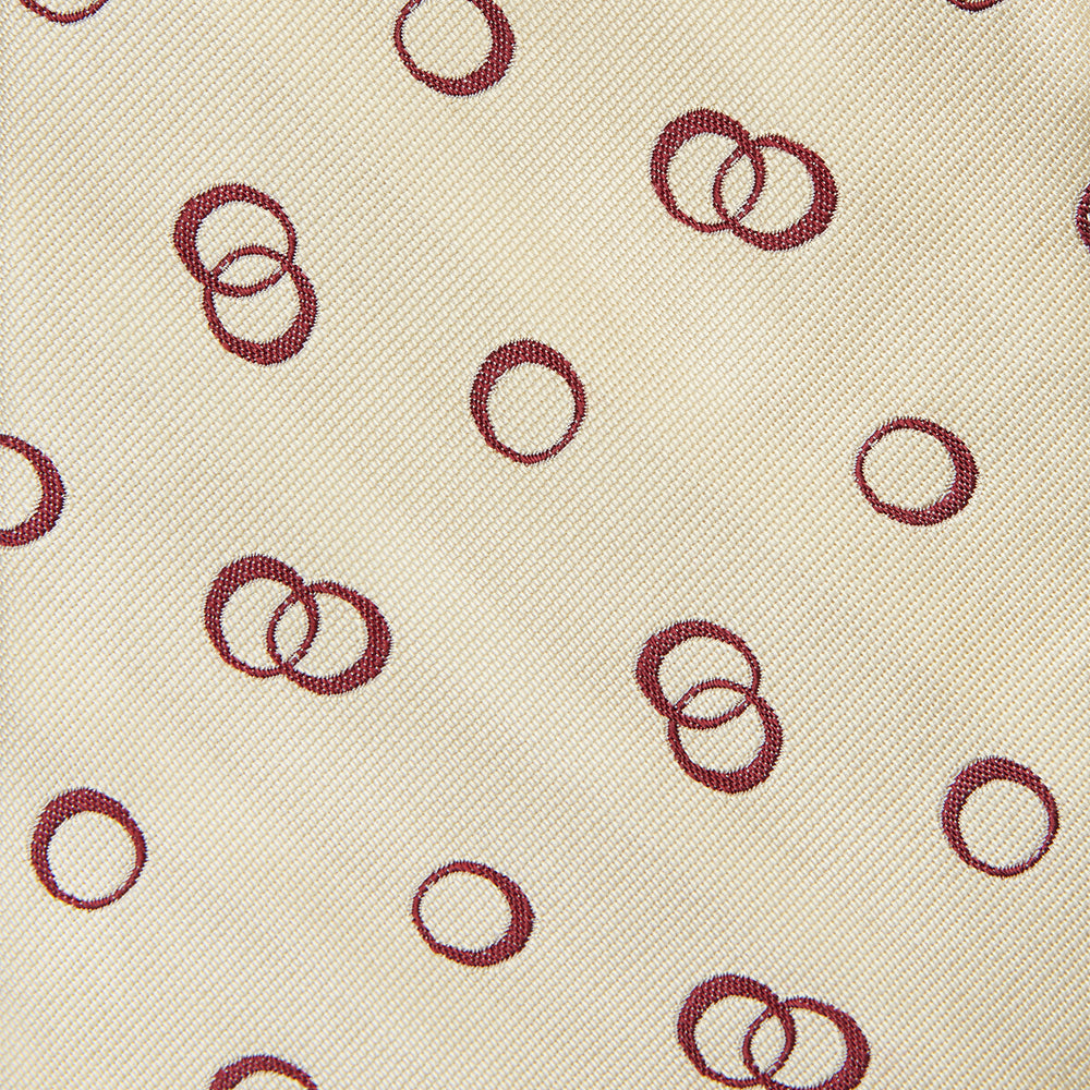 The Yellow Geometric Rings Silk Tie by Turnbull & Asser features a cream silk base with yellow geometric patterns and maroon rings, is hand-finished in England, and is shown rolled up on a white background.