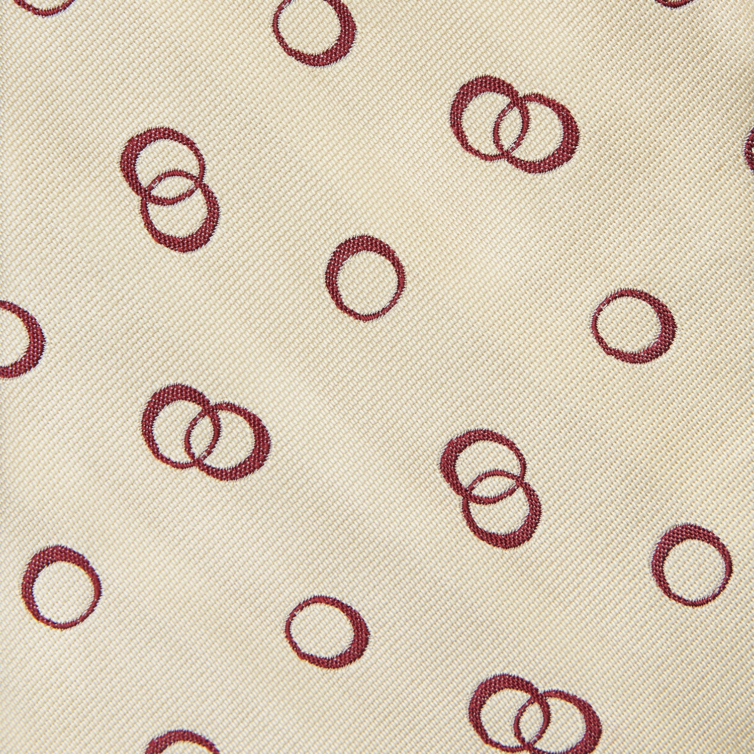 View 3 of product The Yellow Geometric Rings Silk Tie by Turnbull & Asser features a cream silk base with yellow geometric patterns and maroon rings, is hand-finished in England, and is shown rolled up on a white background.
