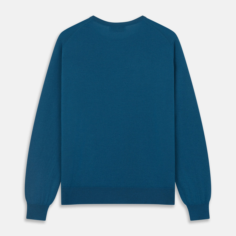 A man with light skin and short brown hair stands against a plain background, wearing the Turnbull & Asser Ocean Blue Merino Kingston Crew Neck Jumper and cream-colored pants, looking directly at the camera with a neutral expression.
