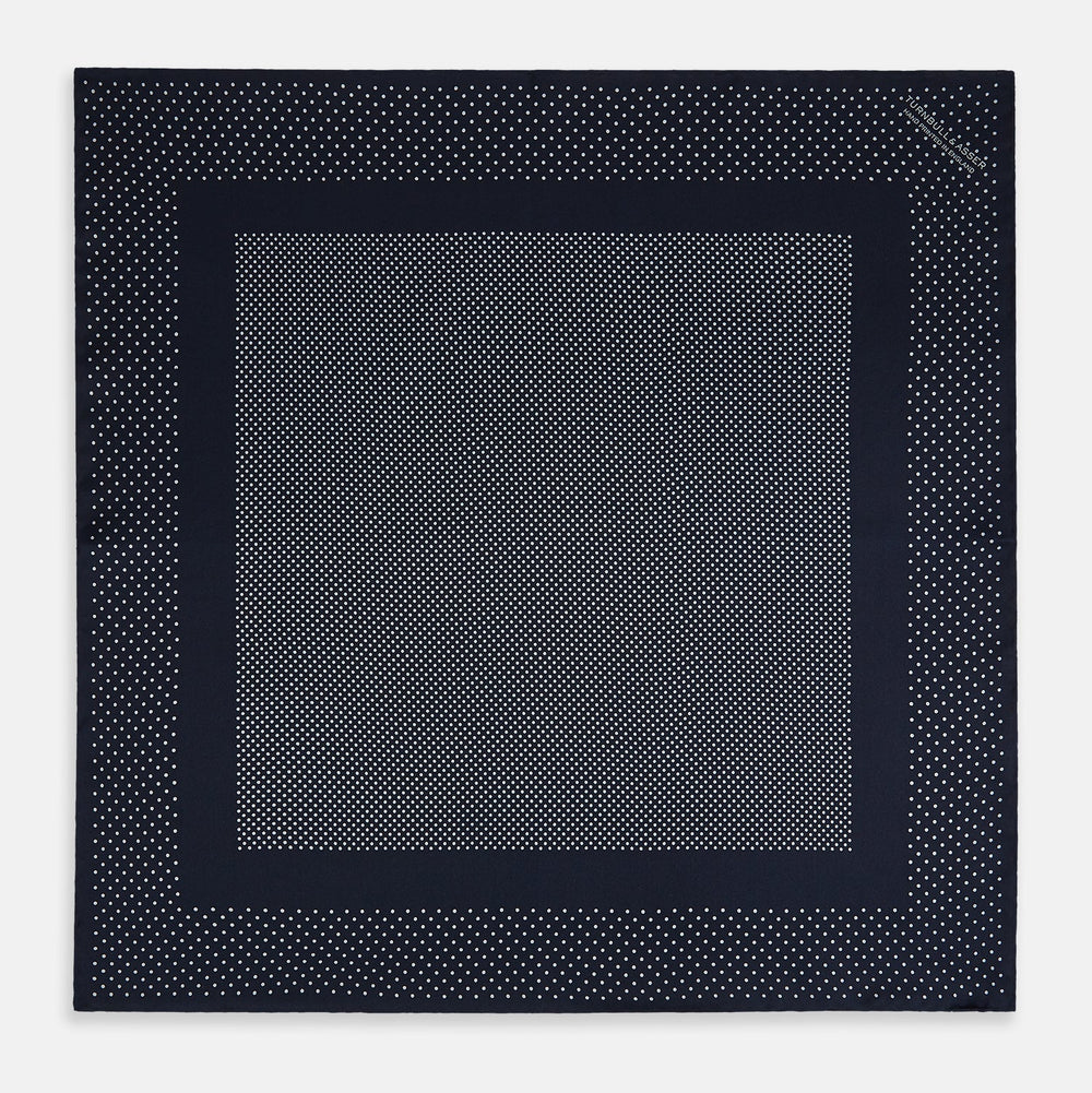 The Turnbull & Asser Navy and Grey Dot Silk Pocket Square features a neatly folded design with small grey dots on navy silk and a solid border, showcasing both sides of the luxurious fabric.
