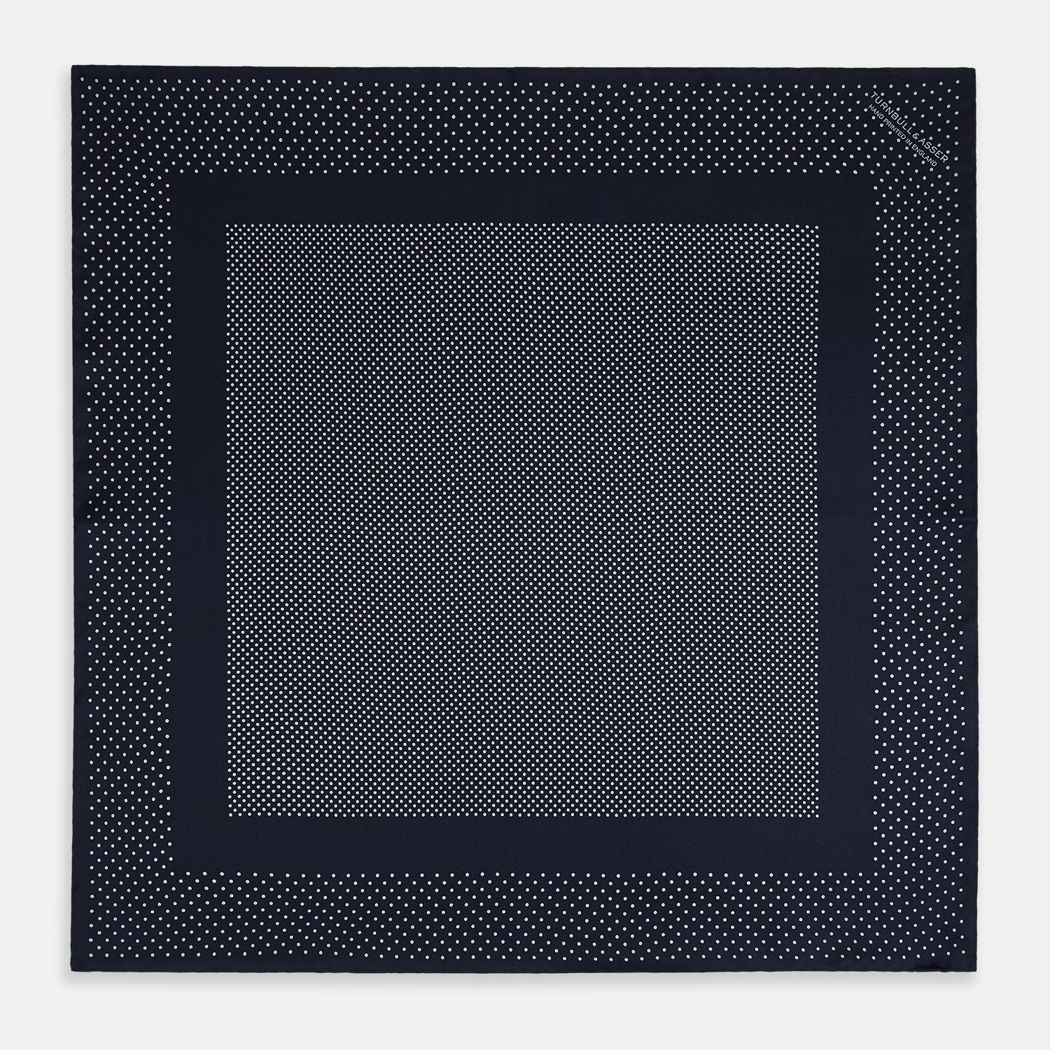 View 4 of product The Turnbull & Asser Navy and Grey Dot Silk Pocket Square features a neatly folded design with small grey dots on navy silk and a solid border, showcasing both sides of the luxurious fabric.