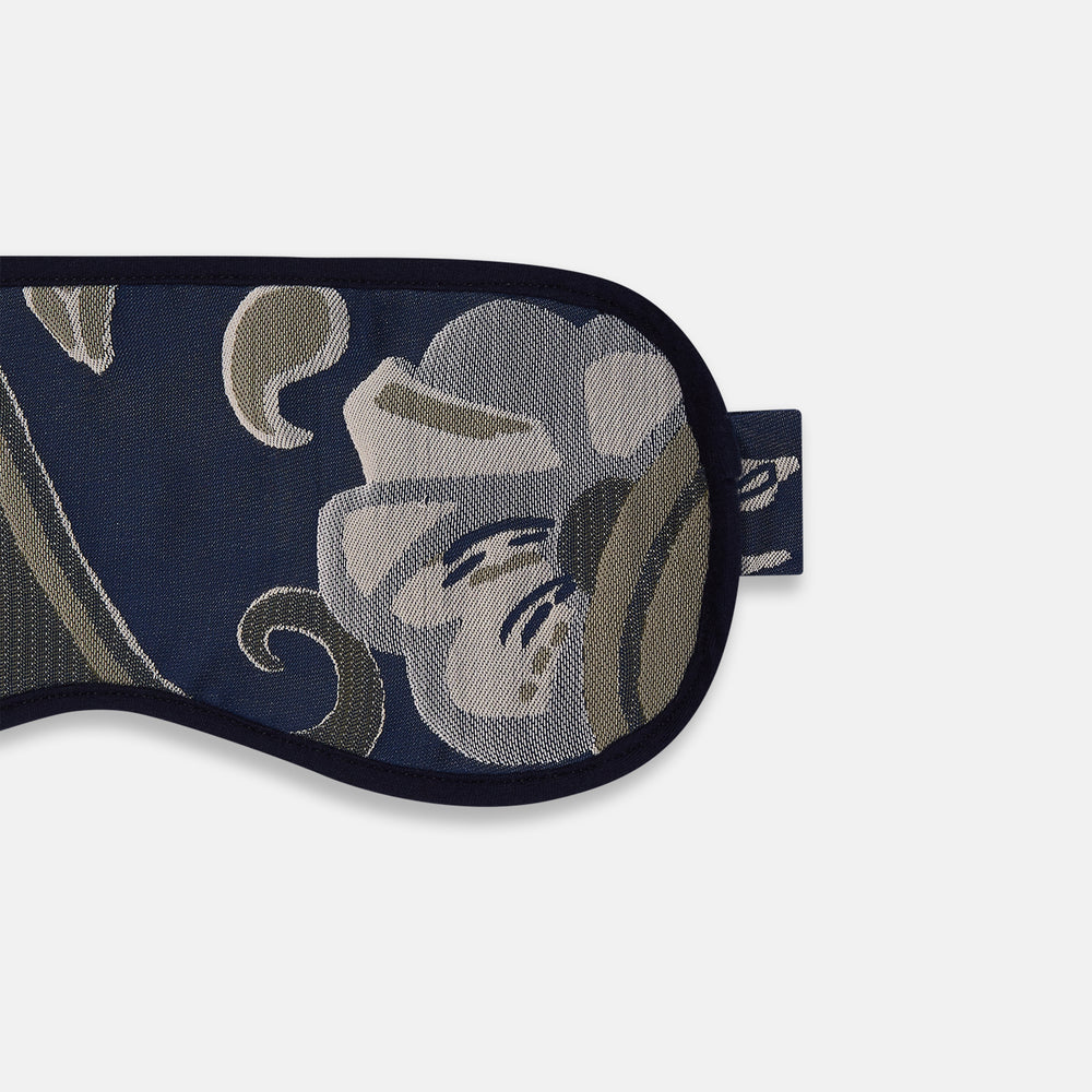 The Turnbull & Asser Navy Bloomsbury Jacquard Cashmere Lined Sleep Mask and Bag features a dark blue backdrop with beige, olive green, and gray floral patterns, plus elastic straps for comfort.