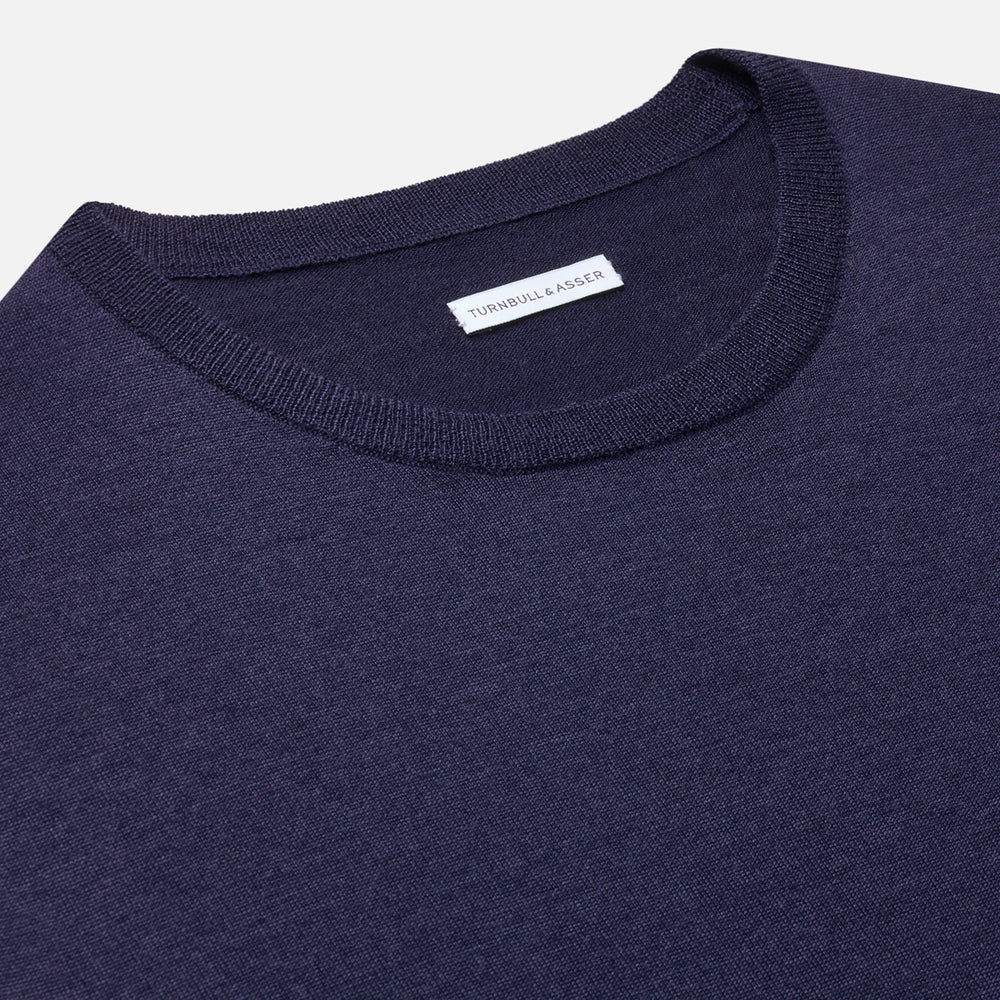 The Turnbull & Asser Navy Merino Round Neck Jumper is shown against a light gray background, featuring a classic long-sleeve design with ribbed cuffs, hem, and neckline for timeless style.