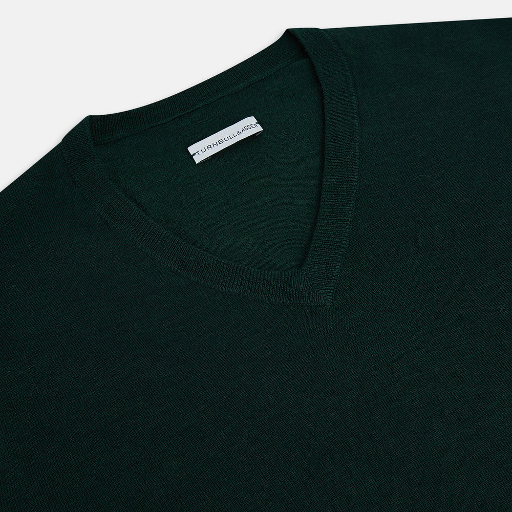 The Turnbull & Asser Forest Green Fine Merino V-Neck Jumper features long sleeves, ribbed cuffs and hem—classic knitwear for any wardrobe, shown on a white background.