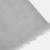 View 2 of product The Grey Cashmere Scarf by Turnbull & Asser, displayed folded with a loose knot on a white background, showcases semi-sheer luxury in light gray—an elegant accessory.