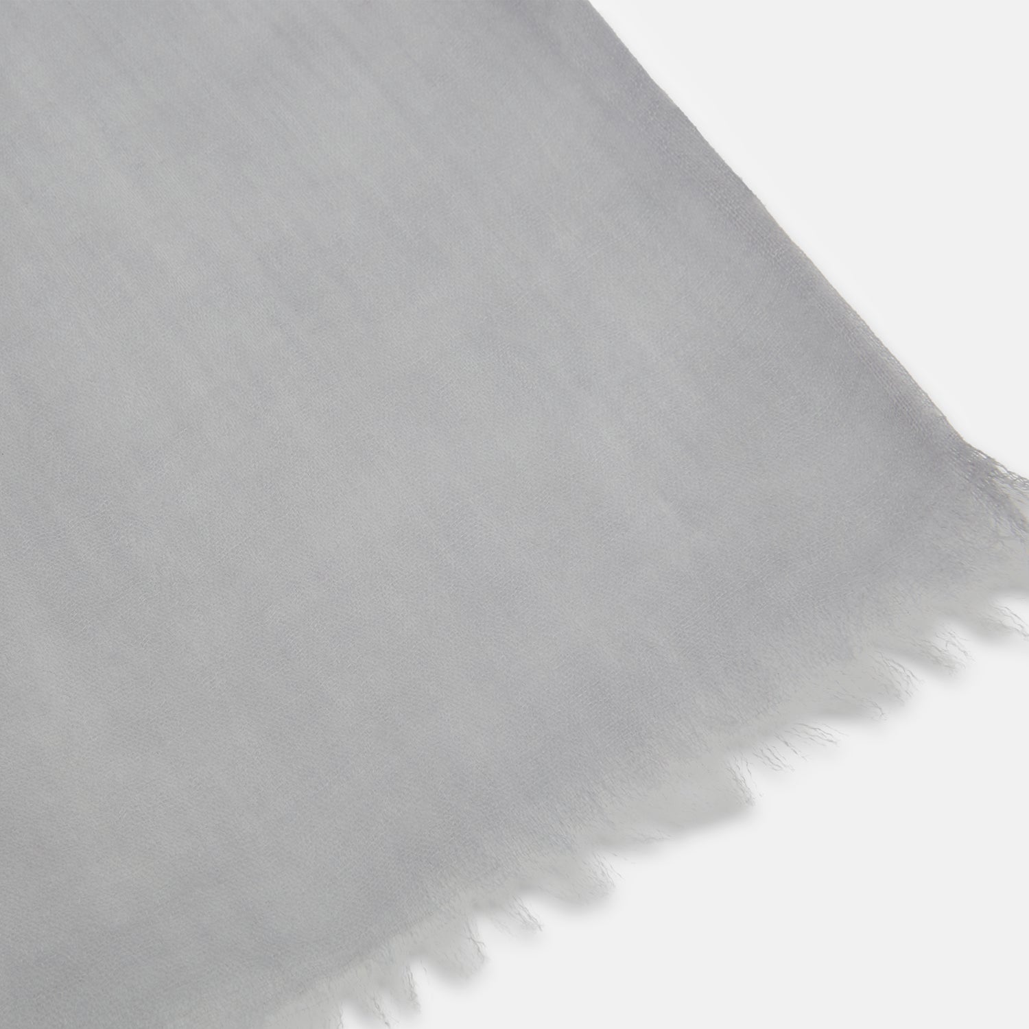 View 2 of product The Grey Cashmere Scarf by Turnbull & Asser, displayed folded with a loose knot on a white background, showcases semi-sheer luxury in light gray—an elegant accessory.