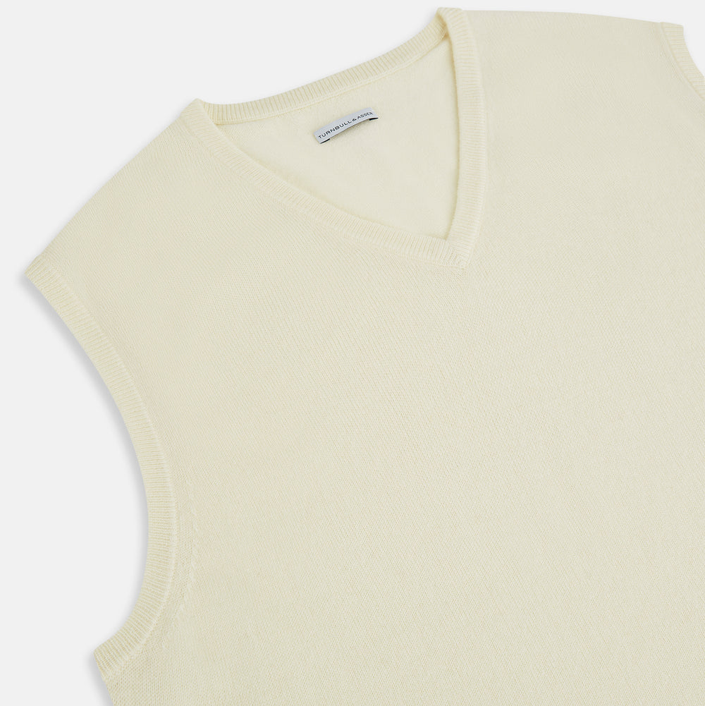 The Turnbull & Asser White Cashmere V-neck Vest is a sleeveless ivory knit with ribbed trim, ideal for layering in cooler weather, shown against a plain white background.