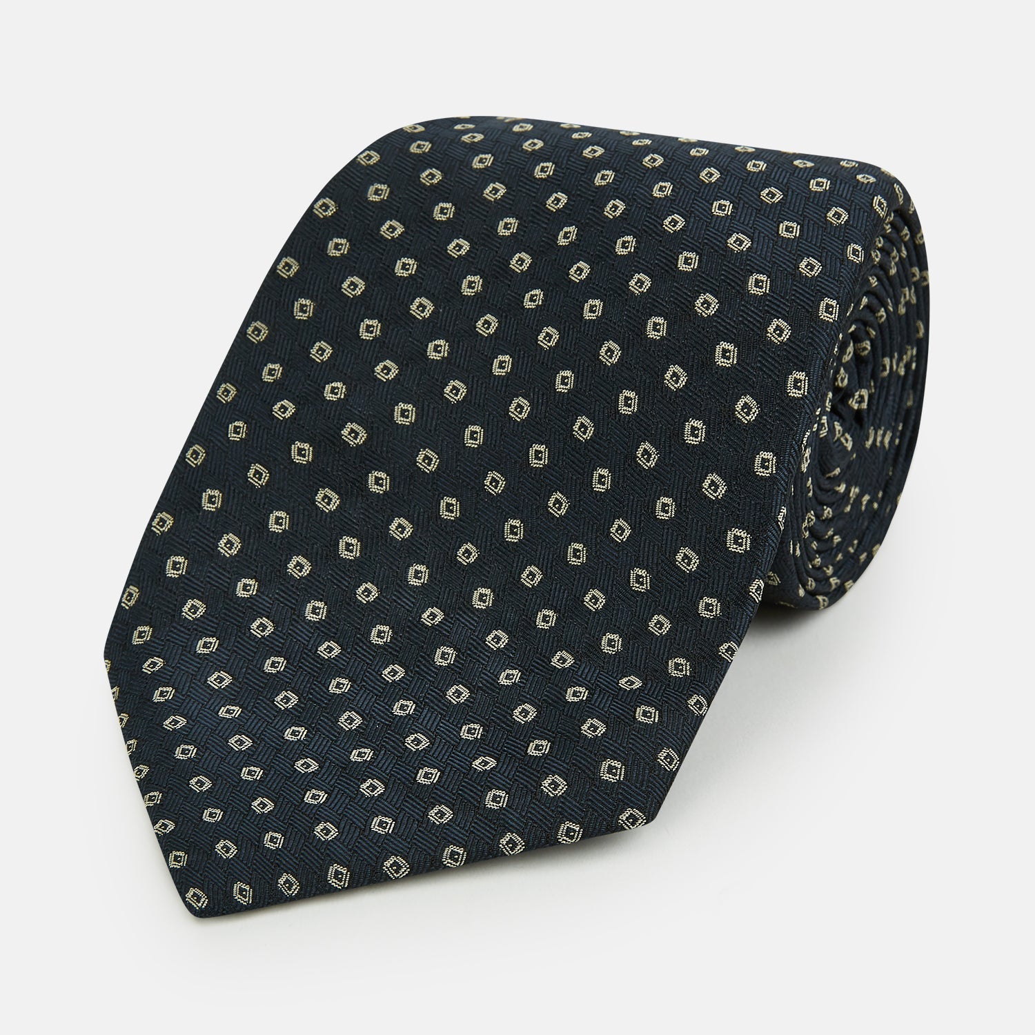 View 1 of product The Turnbull & Asser Navy and White Circle Silk Tie features a repeating circle pattern and is shown rolled on a white background—a timeless men's accessory for any occasion.