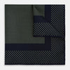 View 1 of product The Turnbull & Asser Navy and Melon Green Dot Silk Pocket Square features small melon green dots on navy silk with a solid border. One corner is folded over to highlight its exquisite handmade craftsmanship.