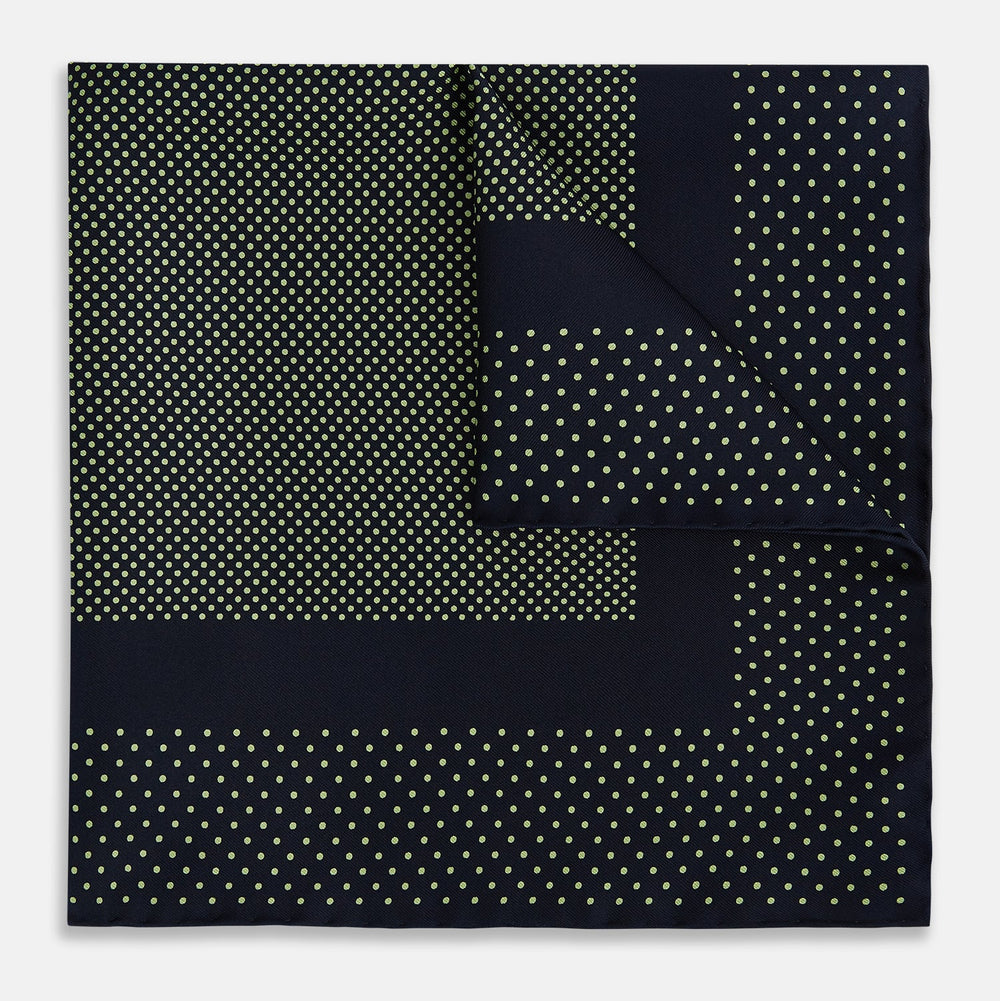 The Turnbull & Asser Navy and Melon Green Dot Silk Pocket Square features small melon green dots on navy silk with a solid border. One corner is folded over to highlight its exquisite handmade craftsmanship.