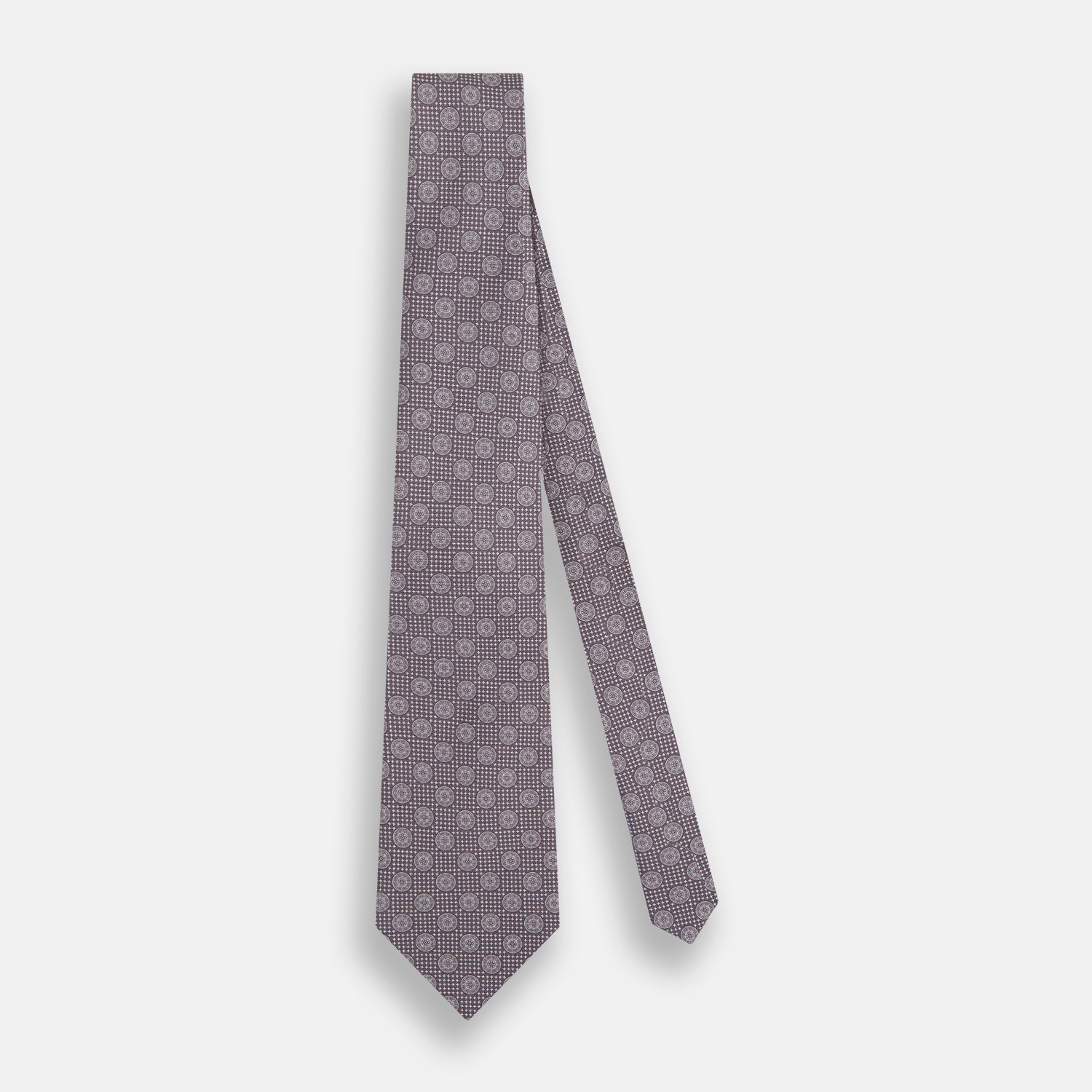 View 2 of product The Turnbull & Asser Ash Medallion Silk Tie features rolled-up ash silk with gray and light purple medallion and grid-like motifs on a white background.