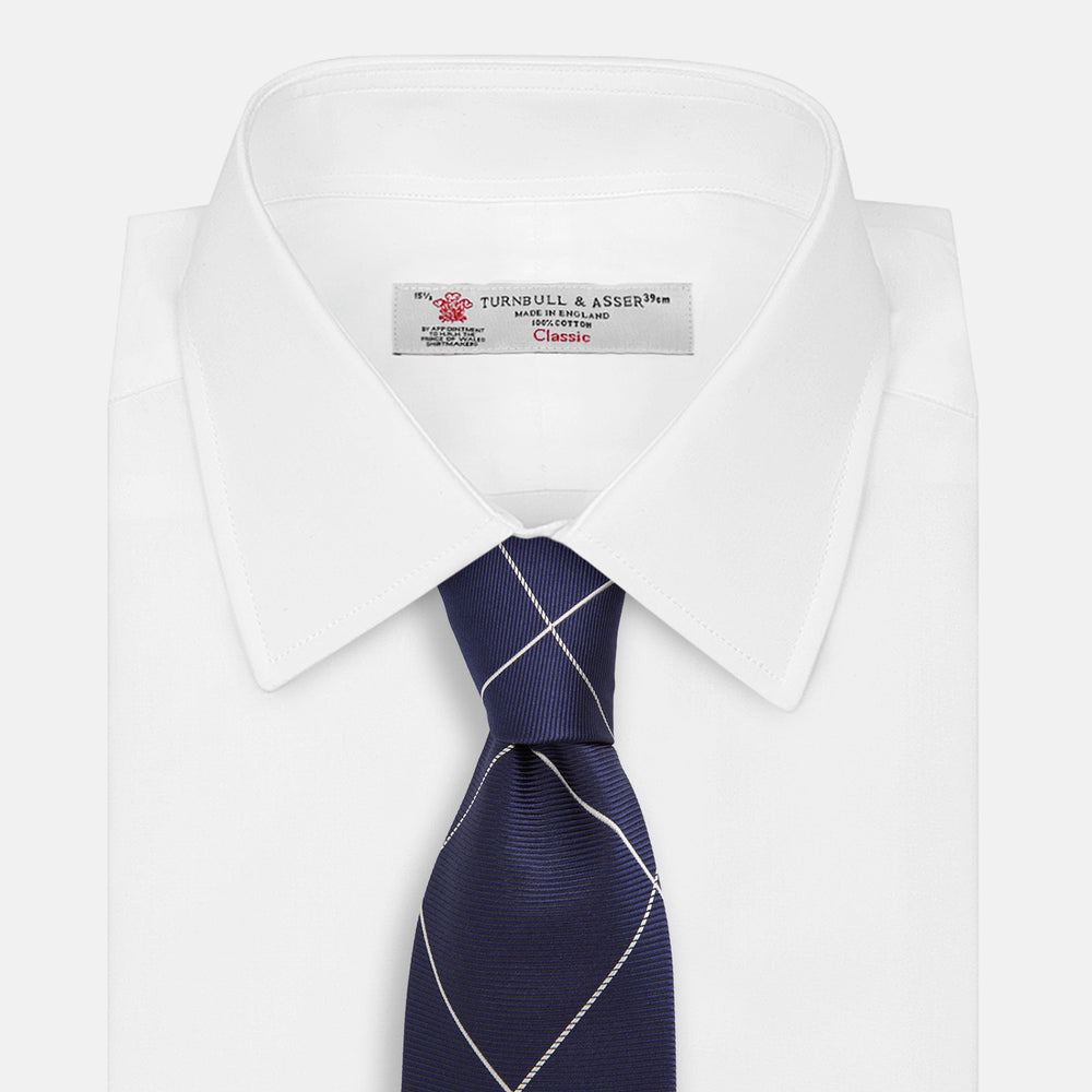 The Turnbull & Asser WINDOW PANE NAVY WHITE TIE features navy blue silk with a subtle diagonal ribbed texture and white windowpane checks, making it the perfect men’s accessory for any formal occasion.