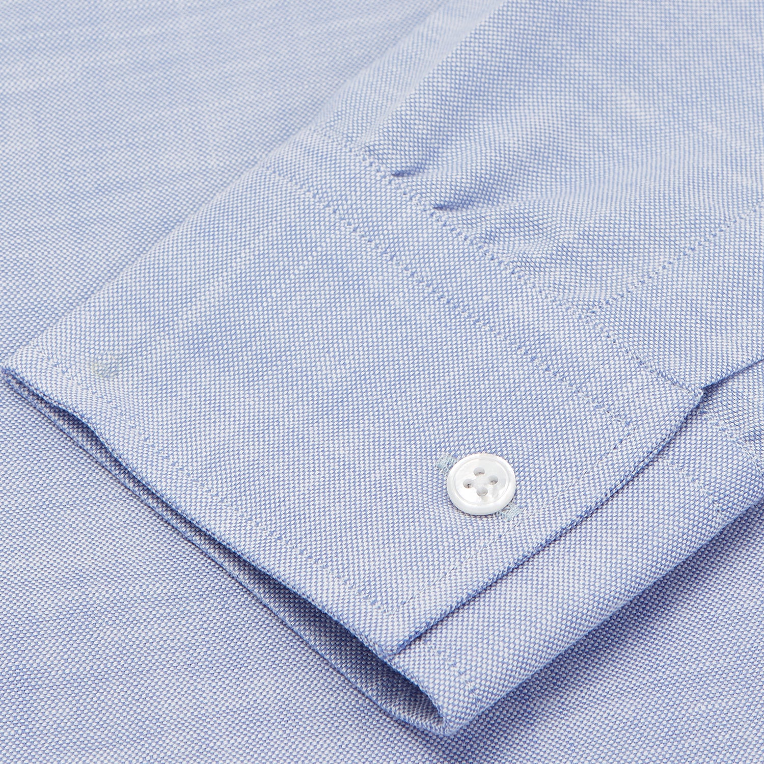 View 3 of product The Turnbull & Asser Mid-Blue Chambray Weekend Fit Shirt features a Dorset collar, white buttons, and 1-button cuffs. It is laid flat on a white background.