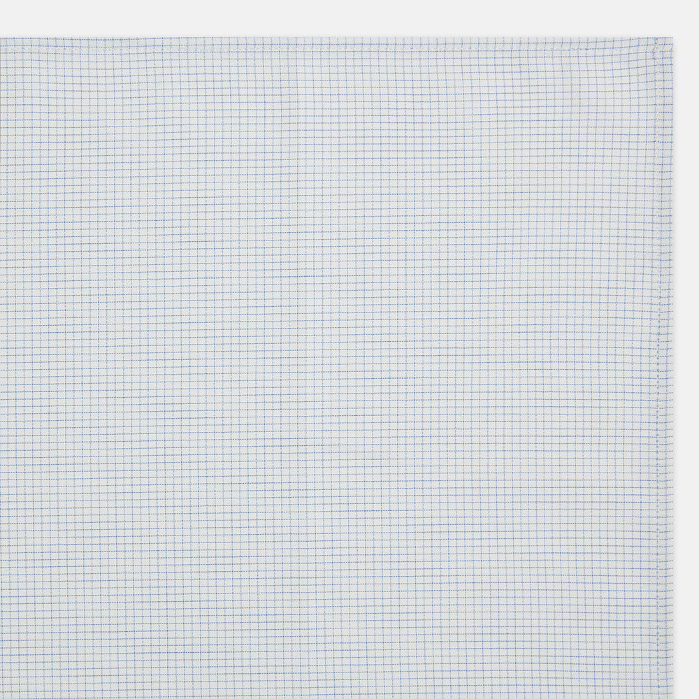 The Turnbull & Asser Hand Rolled Pale Blue Graph Check Handkerchief features a neatly folded white cotton design with a pale blue check, offering an elegant finishing touch to any setting.