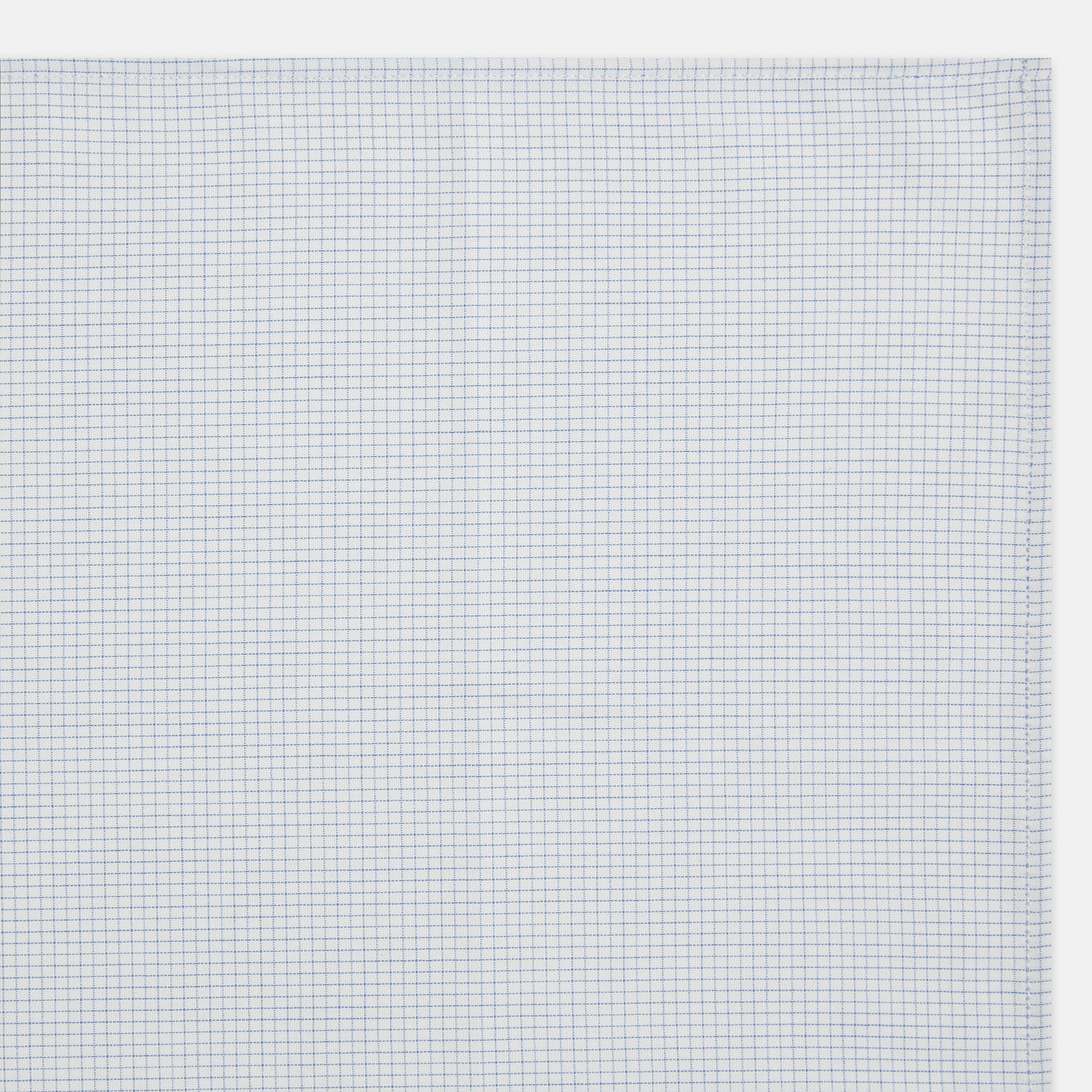 View 3 of product The Turnbull & Asser Hand Rolled Pale Blue Graph Check Handkerchief features a neatly folded white cotton design with a pale blue check, offering an elegant finishing touch to any setting.