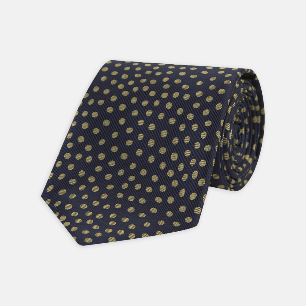 The Turnbull & Asser Navy and Gold Paint Spot Silk Tie features evenly spaced gold spots on classic navy silk, rolled and displayed on a plain white background—ideal for complementing your favorite office shirt.