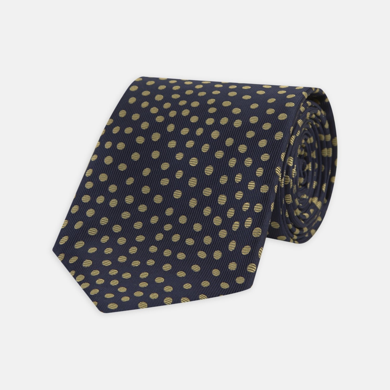 View 1 of product The Turnbull & Asser Navy and Gold Paint Spot Silk Tie features evenly spaced gold spots on classic navy silk, rolled and displayed on a plain white background—ideal for complementing your favorite office shirt.