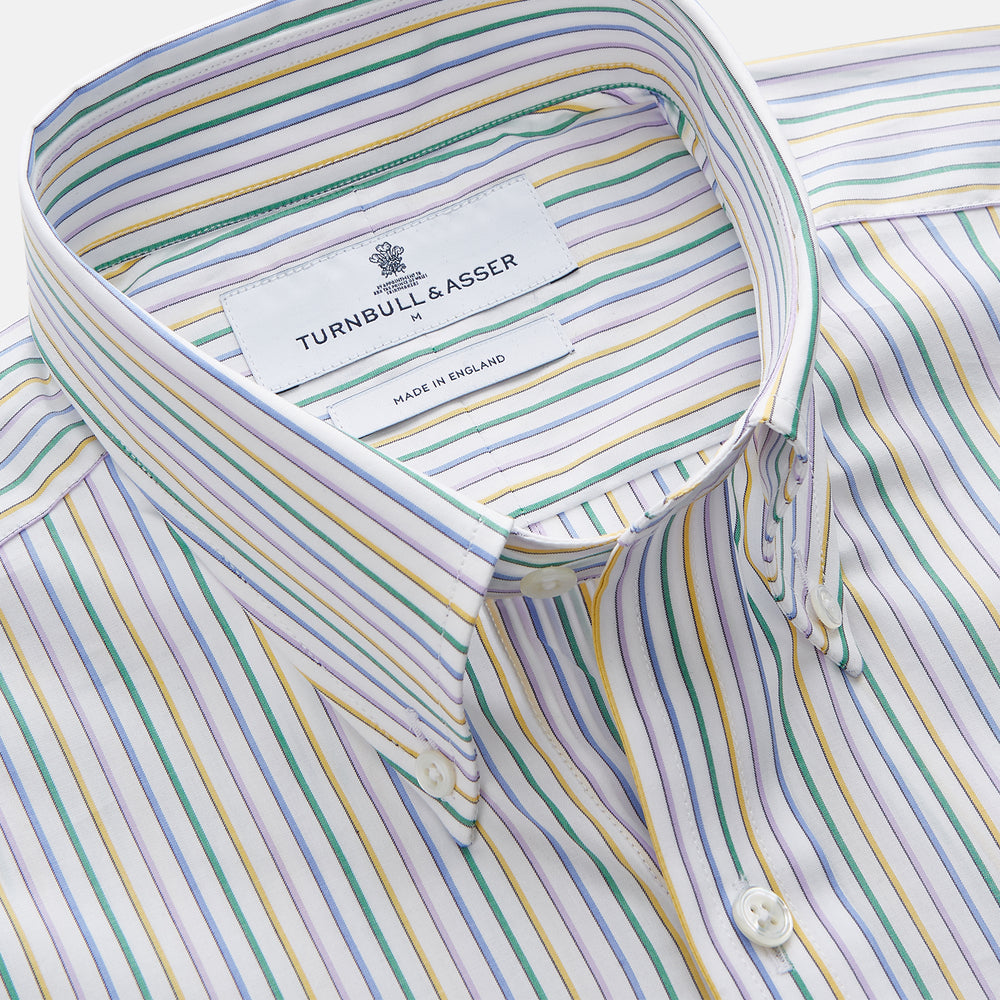 A man wears the Turnbull & Asser Yellow Multi Blazer Stripe Weekend Fit Suffolk Shirt, standing against a beige background with his hands relaxed—a casual look perfect for weekends.