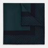 View 1 of product The Turnbull & Asser Navy and Petrol Green Dot Silk Pocket Square features handmade craftsmanship with petrol green polka dots and a darker border, elegantly displayed on a white background.