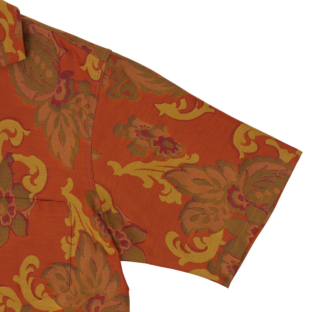 The Orange & Ochre Tapestry Weave Cotton Holiday Fit Shirt by Turnbull & Asser is a short-sleeve, revere collar shirt featuring a yellow and brown floral and leaf pattern on an orange base, finished with white buttons.