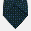 View 4 of product The MINI SQUARE SPOT FOREST GREEN BLUE TIE by Turnbull & Asser is a classic men's accessory, featuring a rolled-up green silk design with small blue geometric patterns—perfect for the modern gentleman.