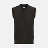 View 1 of product The Turnbull & Asser Dark Brown Cashmere Sleeveless Cardigan has a V-neck, button-up front, two front pockets, and ribbed trim on the armholes and hem, shown against a plain white background.