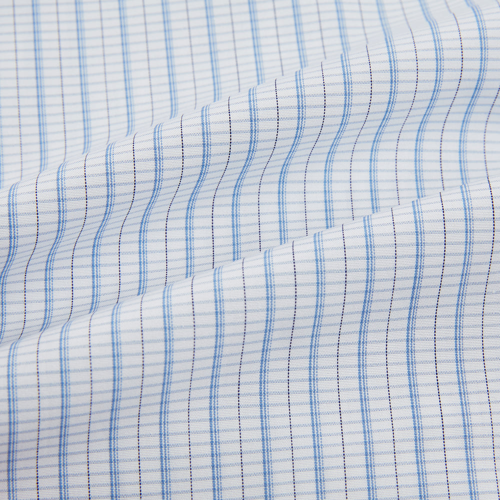 The Turnbull & Asser Blue Graph Check Mayfair Shirt features a classic T&A collar, Mayfair fit, buttoned cuffs, and long sleeves with light blue graph checks on a white background.