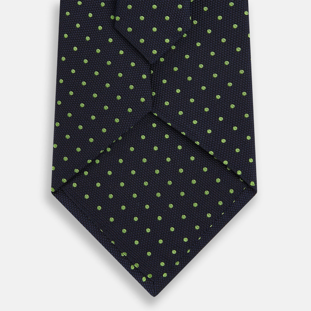 The Turnbull & Asser Green and Navy Micro Dot Silk Tie features small green dots on a navy silk background, displayed rolled up on white.