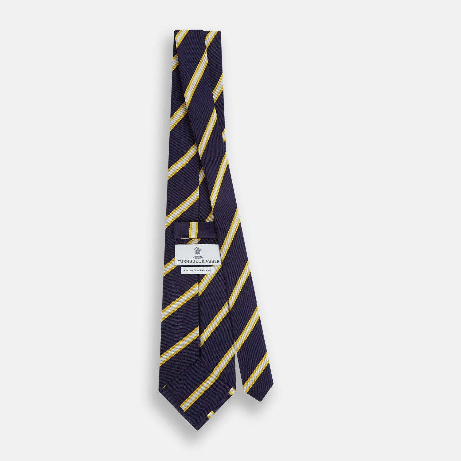 View 2 of product The Turnbull & Asser White and Navy Blazer Silk Tie, featuring diagonal yellow and white stripes, is rolled up neatly on a light gray background.