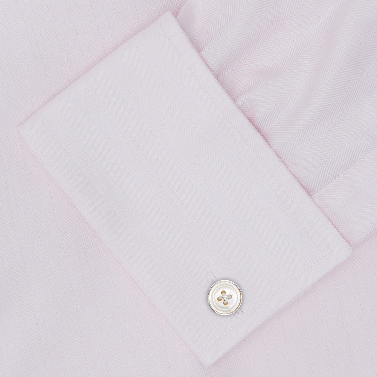 View 6 of product The Turnbull & Asser Pink Herringbone Superfine Cotton Shirt features a T&A collar, double cuffs, and clean-cut design, displayed neatly folded against a white background.
