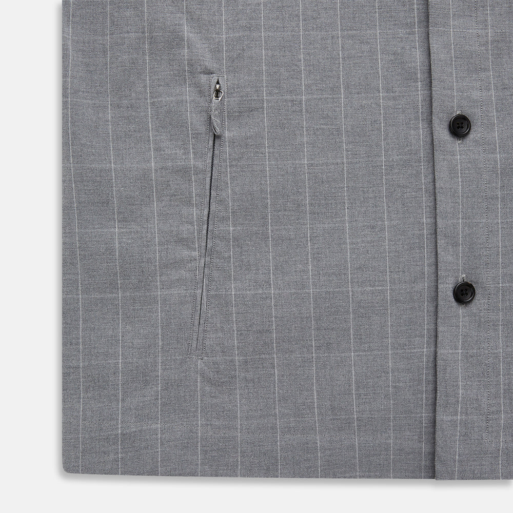 The Turnbull & Asser Grey Check Hampstead Overshirt features a light gray check pattern, pointed collar, chest pocket, and two zippered side pockets, displayed flat against a white background.