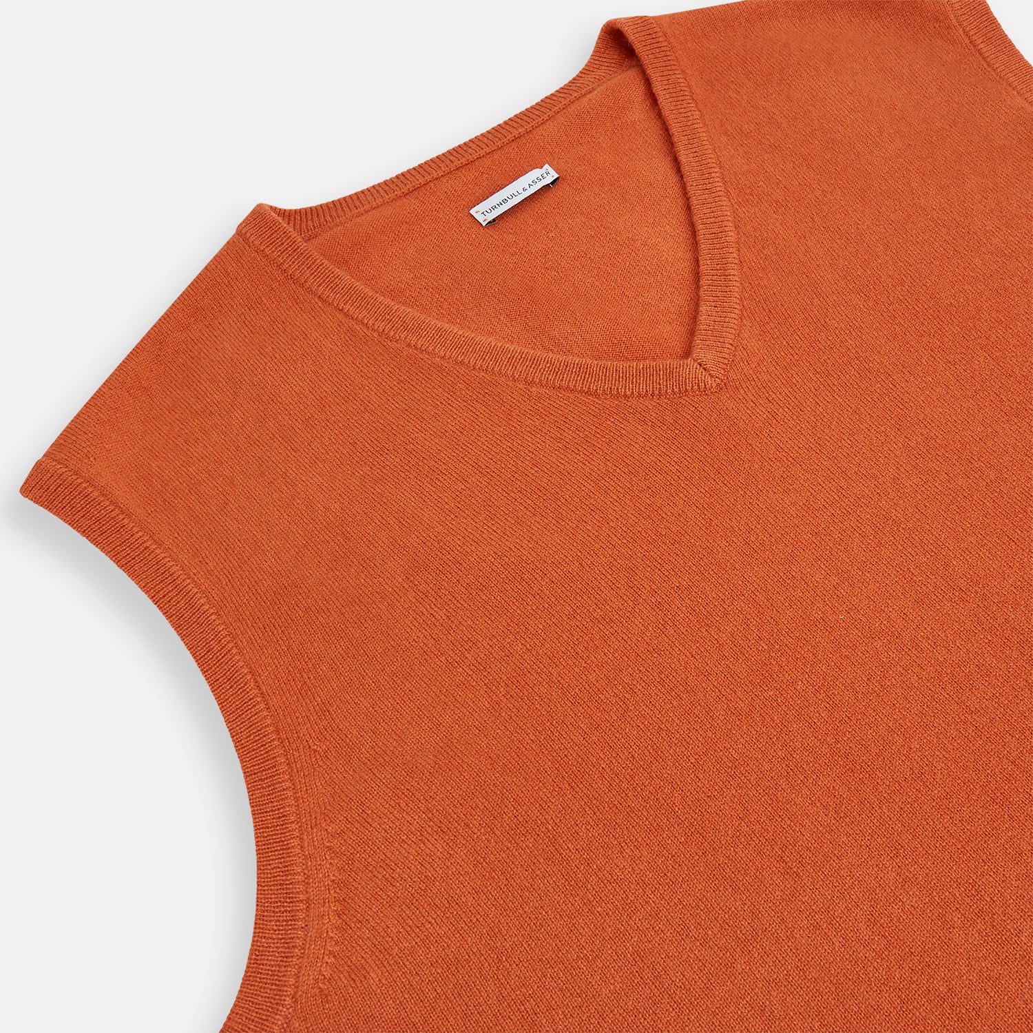 View 2 of product The Turnbull & Asser Orange Cashmere V-Neck Vest adds vibrant style to men’s fashion, featuring a ribbed hem and sleeveless design. Shown against a plain white background.