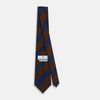 View 4 of product A close-up of the Turnbull & Asser Brown and Navy Block Stripe Silk Tie displays its textured pattern with classic suiting diagonal stripes in navy blue and brown on a light background.