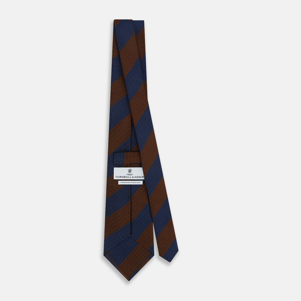 A close-up of the Turnbull & Asser Brown and Navy Block Stripe Silk Tie displays its textured pattern with classic suiting diagonal stripes in navy blue and brown on a light background.