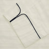 View 3 of product The Cream Pattern Cotton Blend Quin Pyjama Set by Turnbull & Asser features cream stripes, a long-sleeve button-up camp collar shirt with a chest pocket and black piping, and matching drawstring pants.