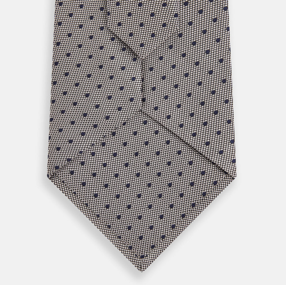 The Turnbull & Asser Navy and Lilac Micro Dot Silk Tie is shown rolled up on a white background, featuring a refined pattern of small lilac dots on navy silk.