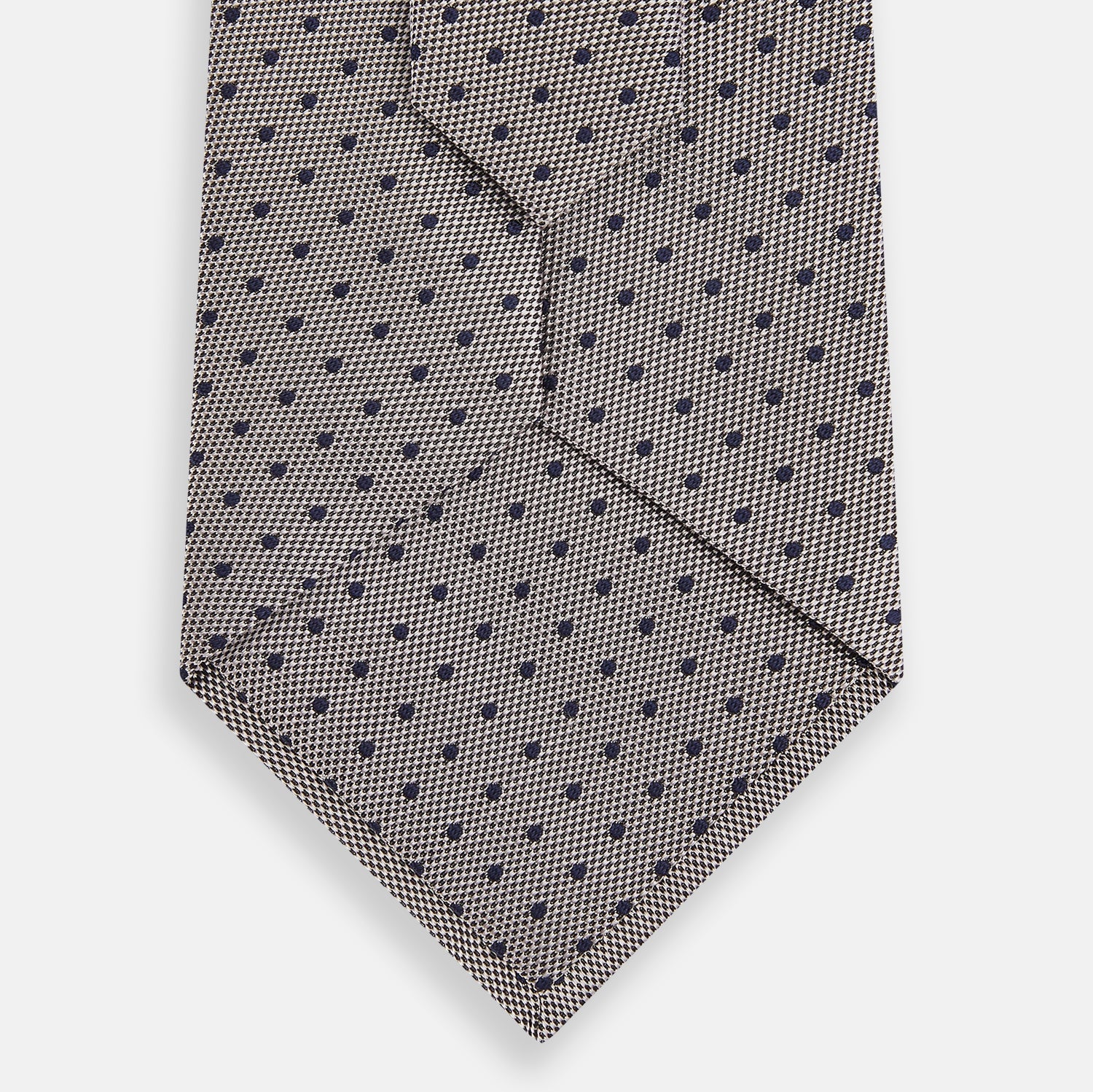 View 3 of product The Turnbull & Asser Navy and Lilac Micro Dot Silk Tie is shown rolled up on a white background, featuring a refined pattern of small lilac dots on navy silk.
