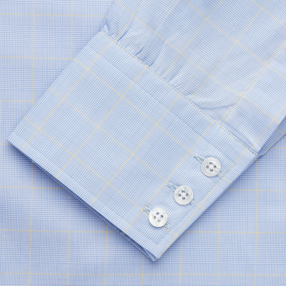 The Yellow and Blue Prince of Wales Check Belgravia Shirt by Turnbull & Asser features a classic collar, white buttons, long sleeves, and a checked pattern, displayed laid flat on a white background.
