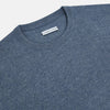 View 2 of product The Turnbull & Asser Pacific Blue Cashmere Round Neck Jumper features long sleeves and ribbed cuffs, hem, and neckline, shown on a light grey background.