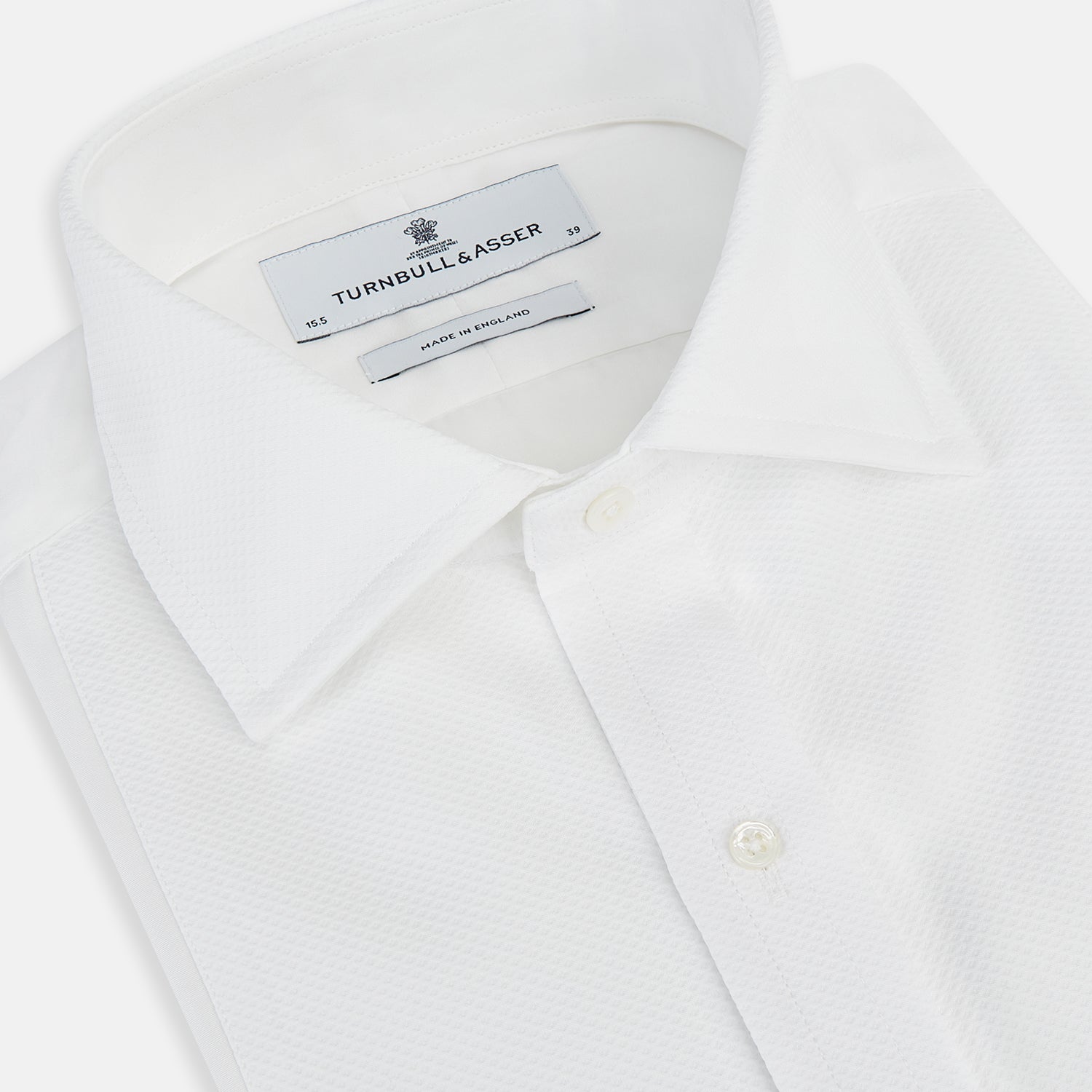 View 2 of product The Turnbull & Asser Tailored Fit White Marcella Front Shirt features a Kent Collar and double cuffs, shown laid flat on a white background. Perfect as a black tie shirt for formal events.