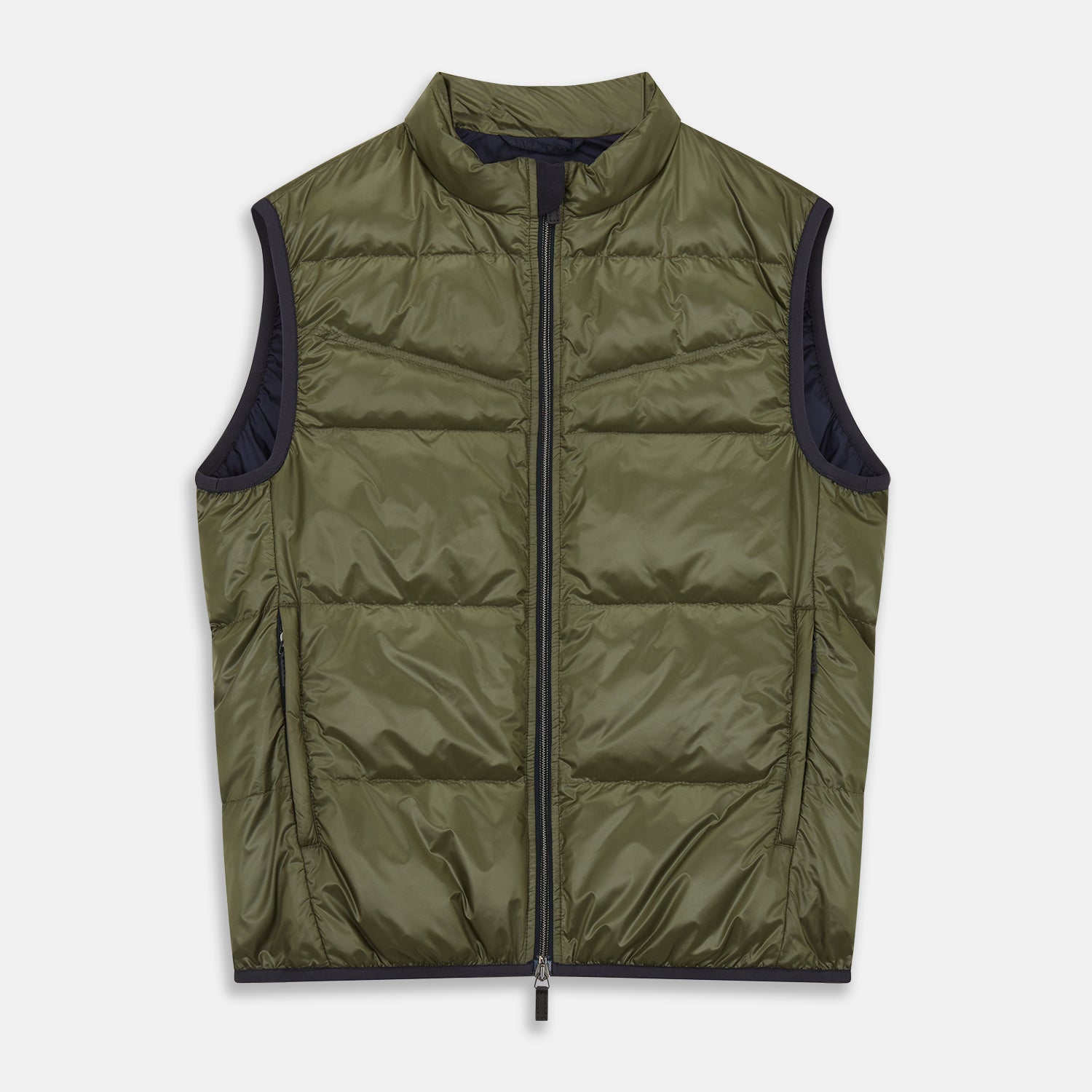 View 2 of product A man stands against a plain background wearing the Turnbull & Asser Green Peyton Sealup Quilted Gilet over a striped shirt, dark trousers, and white sneakers, with his hands in his pockets and looking slightly to the side.