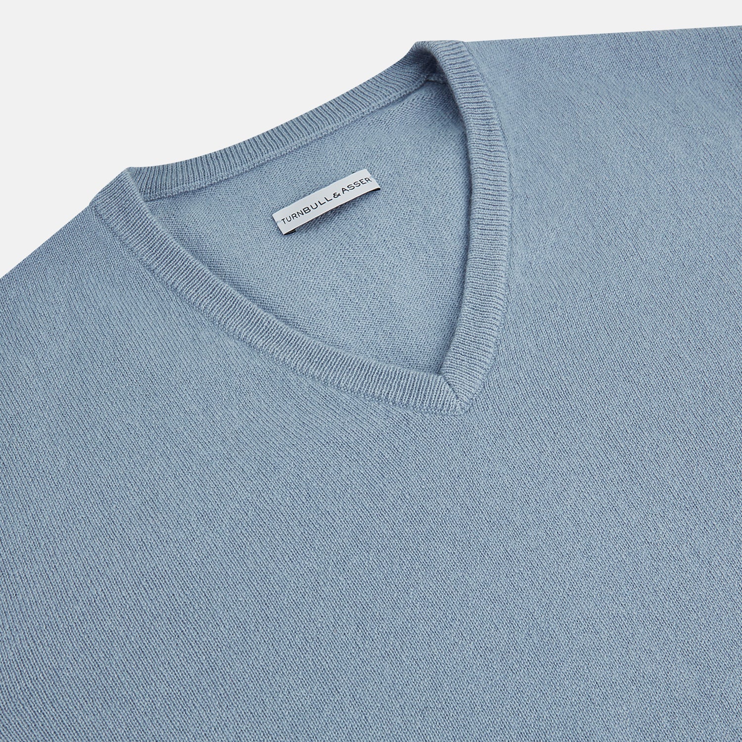 View 2 of product The Turnbull & Asser Frost Blue Cashmere V-Neck Jumper features ribbed cuffs, hem, and neckline. This elegant long sleeve knitwear piece is shown on a plain white background.
