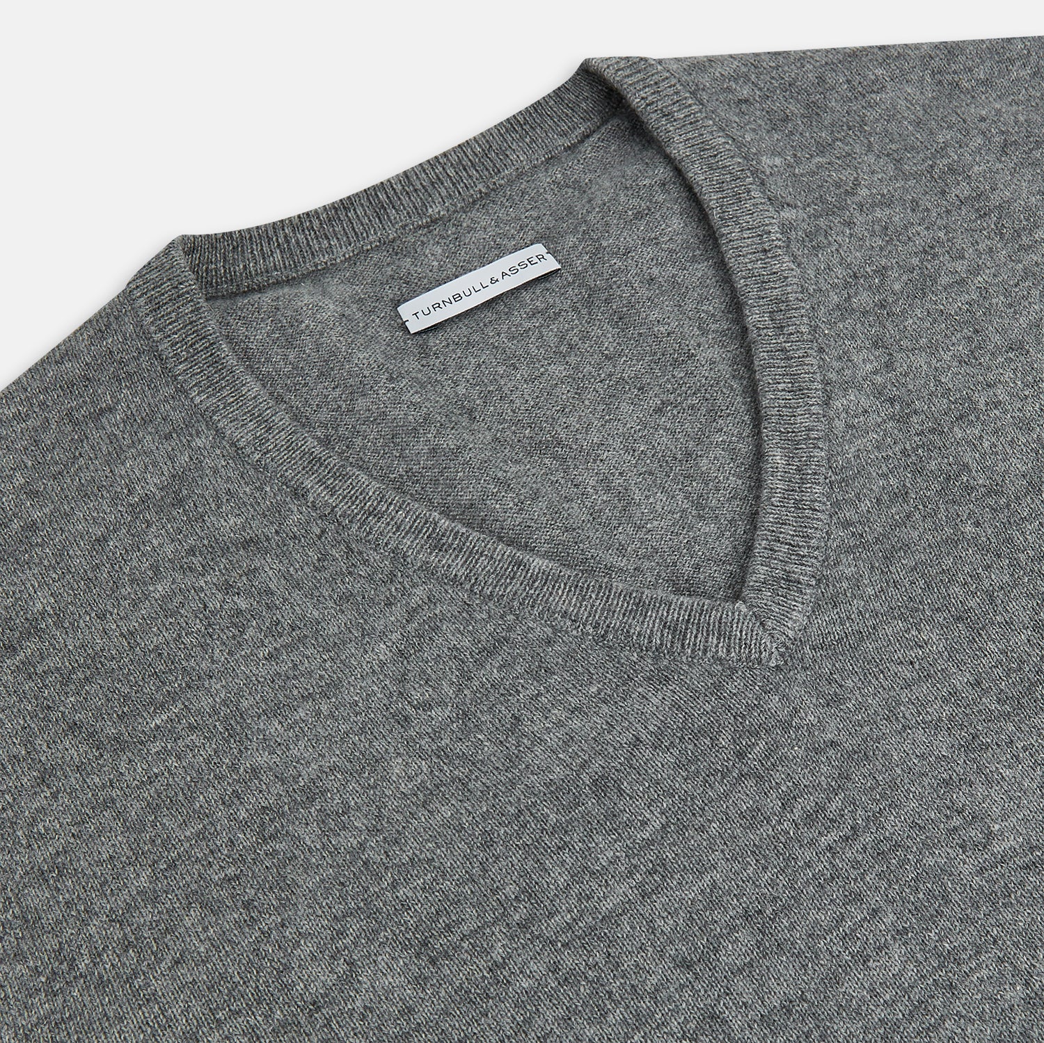 View 2 of product The Turnbull & Asser Grey Melange Cashmere V-neck Jumper features long sleeves, ribbed cuffs and hem, showcasing timeless style against a white background.