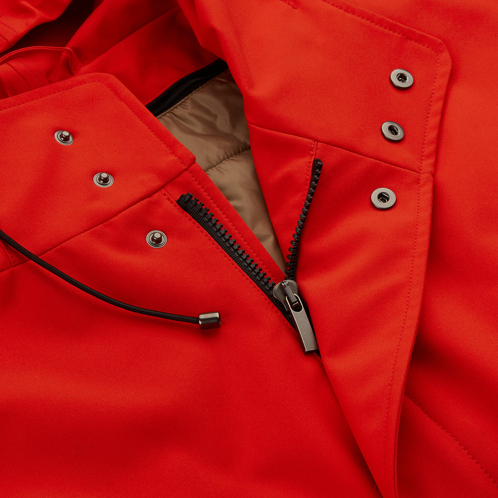 Wearing the Turnbull & Asser Red Walter Sealup Parka with Detachable Liner, black pants, and white sneakers, a person stands in profile against a plain light background—perfect for travel.